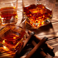 Vintage cognac with cigar over wooden background